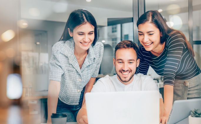 Three colleagues looking at a laptop together.